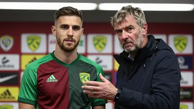 A 50-year-old, 5'9" Belgian winger with a lean build, mid-30s, wearing Norwich City's home kit in green and dark red, the...