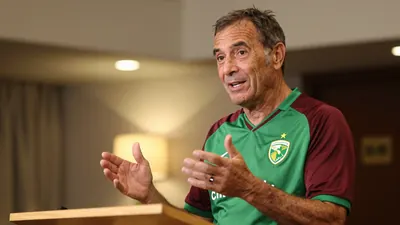 A 50-year-old man with a rugged, weathered complexion, wearing a Norwich City home kit with a prominent green shirt and...