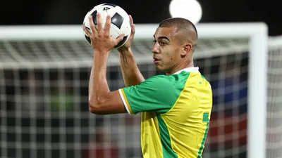 A photorealistic image of a 22-year-old, 5'9" (175 cm) tall, Australian striker with a shaved head, wearing a green and...