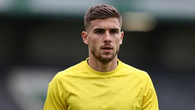 A mid-20s anonymous Norwich City staff member in a tight-fit yellow training kit, head-and-shoulders shot, background...
