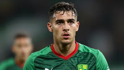 Mid-30s Norwich City forward, athletic build, intense gaze, head-and-shoulders, wearing the green and dark-red home shirt...