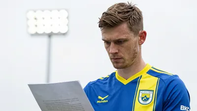 A 30-year-old, 6'1'' tall, male, Norwich City coach, wearing a blue and yellow football kit, and sharp focus on the eyes...