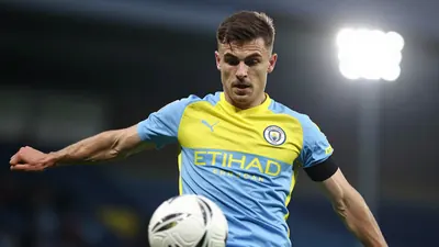 A tight action crop of an anonymous Norwich City player in a blue and yellow jersey, with a white ball at their feet...