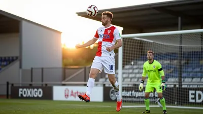 A tight action shot of Ante Crnac, a 30-year-old Croatian striker, heading the ball away from Cambridge United's Glen...