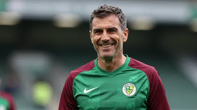Middle-aged, fit manager with short dark hair, smiling broadly, head-and-shoulders, wearing Norwich City home kit - green...
