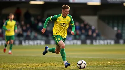 A tight action crop of an anonymous Norwich City midfielder, dressed in a green and yellow jersey, sprinting down the...