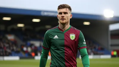 A determined 28-year-old Norwich City midfielder, wearing the green and dark red home kit with the Canaries' crest on the...